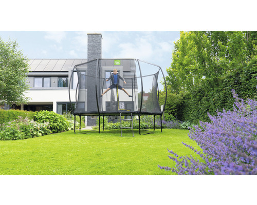 Garçon sautant sur un trampoline de jardin avec filet de sécurité