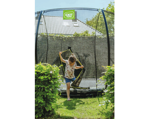 Une fille entre dans un trampoline de jardin avec filet de sécurité de Exit Toys.