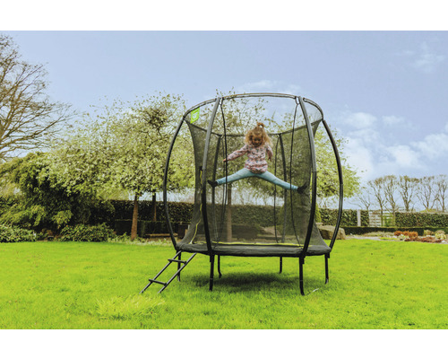 Fille sautant sur un trampoline de jardin avec filet de sécurité et échelle