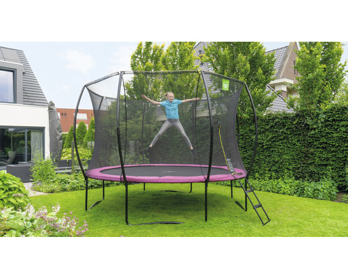 Mädchen springt auf Gartentrampolin mit Sicherheitsnetz und Leiter