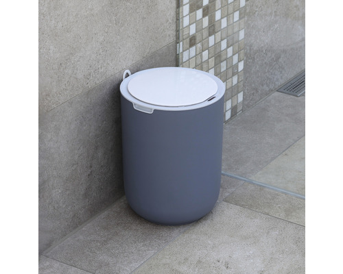 Scène de salle de bains avec une poubelle à pédale ronde en plastique avec couvercle