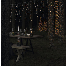 Dekorierte Gartenszene mit Lichterketten, Tisch, Sitzbank und Lampen für eine stimmungsvolle Atmosphäre.