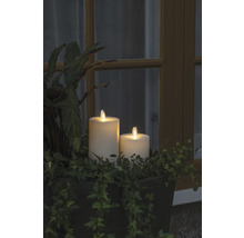 Deux bougies LED en cire véritable dans une jardinière avec des plantes vertes