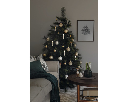 Sapin de Noël décoré avec des boules et des bougies à côté d''un canapé et d''une table