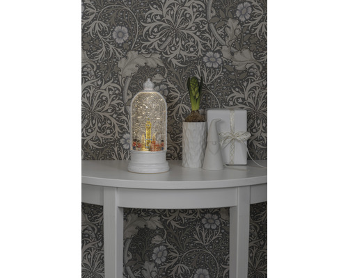 Scène décorative avec boule à neige, plante, gnome et cadeau sur une table