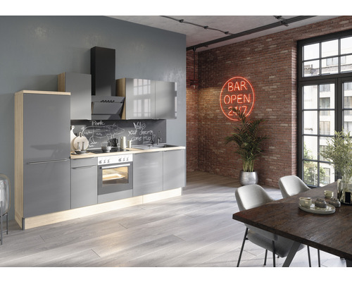Cuisine moderne avec armoires grises, hotte aspirante et appareils intégrés dans une pièce avec mur en briques et table à manger
