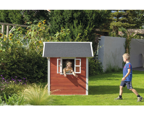 Enfant dans cabane de jeu en bois dans le jardin