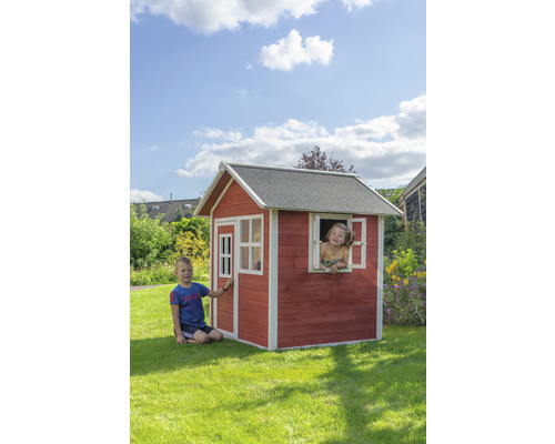 Des enfants jouent dans une cabane en bois avec une porte et des fenêtres dans le jardin.