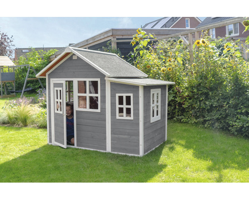 Graues Holzspielhaus mit Fenstern und Tür im Garten mit spielenden Kindern