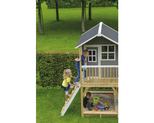 Maisonnette avec bac à sable et enfants jouant dans le jardin.