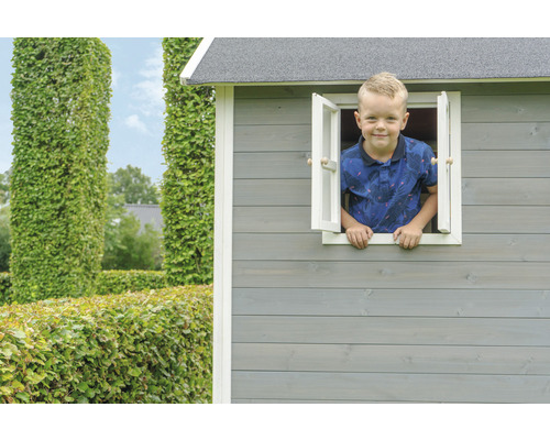 Garçon regarde par la fenêtre d''une cabane en bois