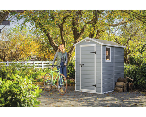 Gartenszene mit Gerätehaus, Fahrrad und Frau im Garten