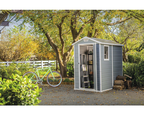 Gartenszene mit Gerätehaus, Fahrrad, Leiter, Regal und Holzstapel