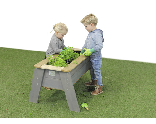 Deux enfants jardinent dans un potager surélevé en bois dans le jardin.
