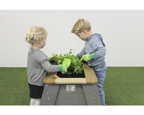 Deux enfants jouent avec un potager surélevé dans le jardin.