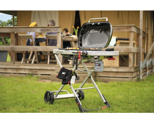 Weber Traveler Gasgrill mit Grillwerkzeugen und Gasflasche vor dem Zelt