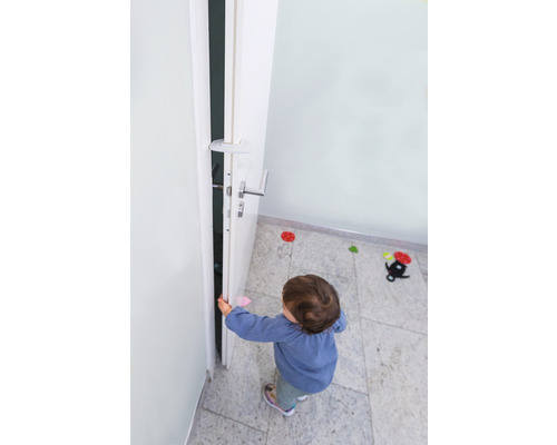 Un enfant ouvre une porte avec un butoir de porte pour la sécurité des enfants