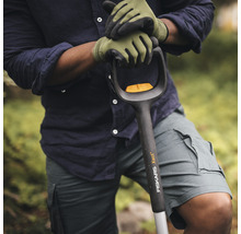 Eine Person mit Gartenhandschuhen hält einen Spaten der Marke Fiskars.