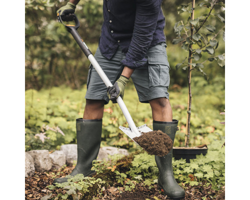 Une personne creuse un trou dans le jardin avec une bêche.
