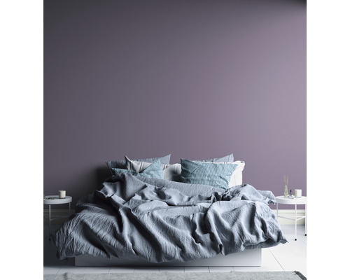 Schlafzimmer mit Bett, Nachttischen und lila Wand