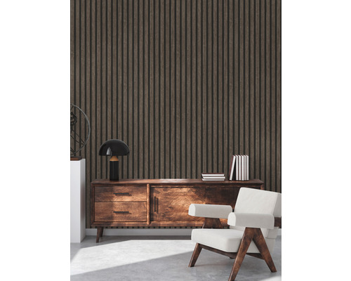 Intérieur avec un revêtement mural en panneaux de bois, un buffet, une lampe, des livres et un fauteuil.