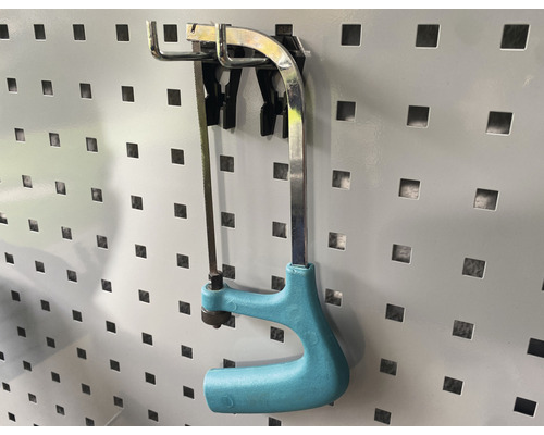 Scie à métaux avec poignée en plastique sur un panneau perforé