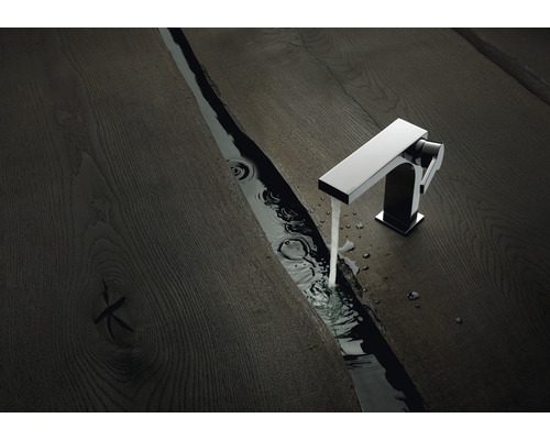 Robinet de lavabo sur surface en bois foncé avec écoulement d''eau dans une rigole