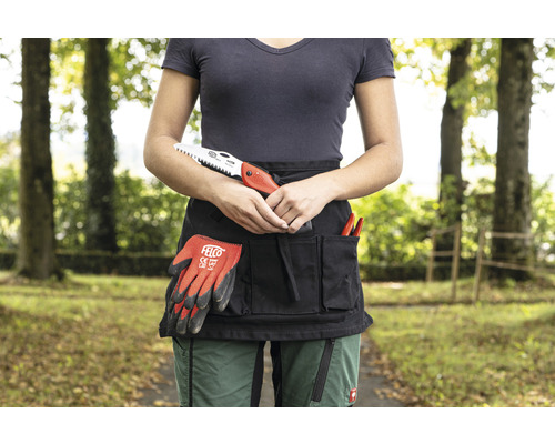 Person mit Gartenschürze mit Gartengeräten, Handschuhen und einer Säge