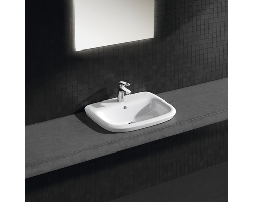 Lavabo en céramique avec robinet sur une surface de rangement dans une salle de bains