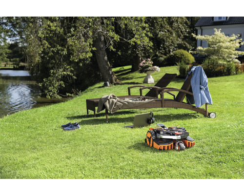 Robot tondeuse sur une pelouse avec des chaises longues et un étang à l''arrière-plan