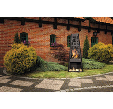 Schwarzer Gartenkamin mit Holzscheiten vor einem Backsteingebäude