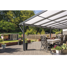 Terrasse mit Überdachung, Gartentisch und Gartenstühlen vor begrüntem Hintergrund