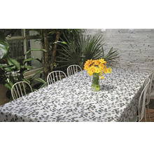Tisch mit blättergemusterter Tischdecke und gelben Blumen in einer Vase