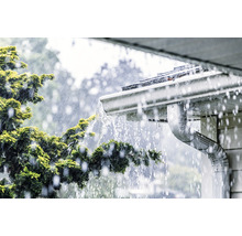 L''eau de pluie s''écoule d''un toit dans une gouttière.