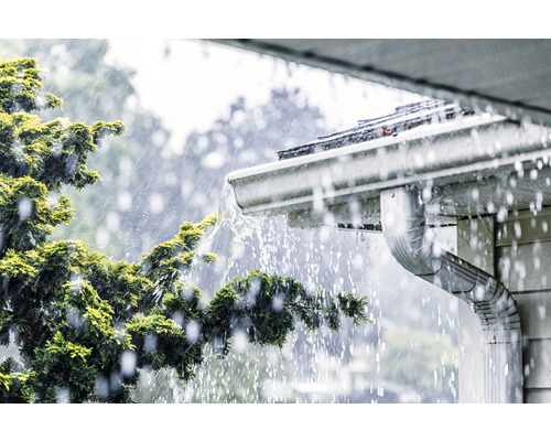 L''eau de pluie s''écoule d''un toit dans une gouttière.