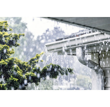 L''eau de pluie s''écoule d''un toit dans une gouttière