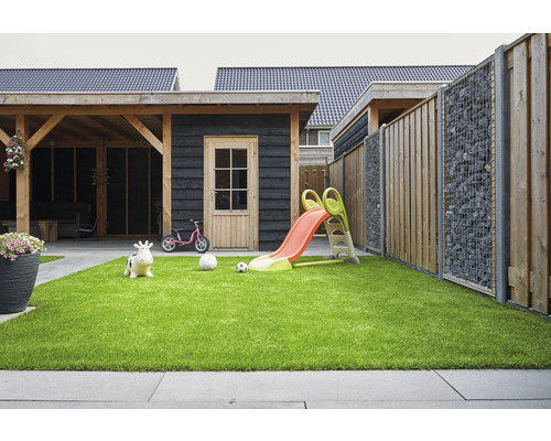 Scène de jardin avec pelouse, clôture en gabion, abri de jardin et aire de jeux