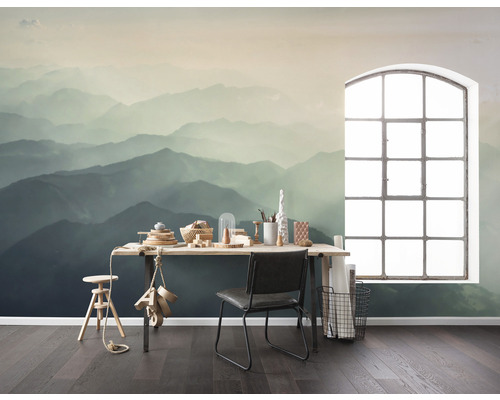 Une pièce avec un papier peint photo représentant un paysage de montagne, un bureau, une chaise et une fenêtre.