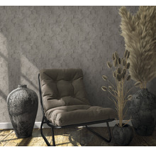 Scène avec fauteuil, vases et herbes décoratives devant un mur à motif hexagonal.