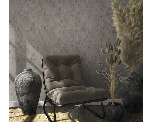 Scène avec fauteuil, vases et herbes décoratives devant un mur à motif hexagonal.