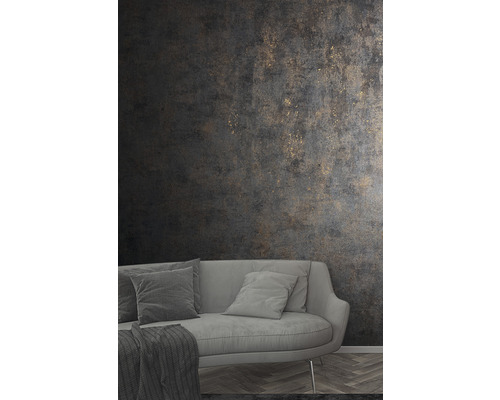 Salon avec canapé gris et papier peint structuré foncé avec des accents dorés.