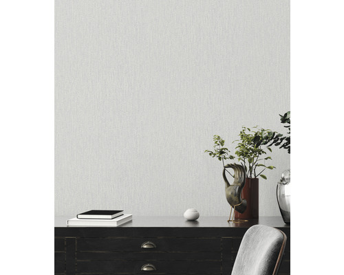 Intérieur décoratif avec papier peint structuré au mur, livres sur un buffet sombre avec plante en pot et décorations