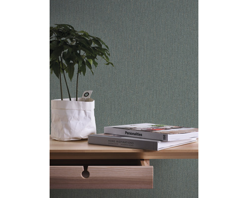 Gros plan d''une table avec tiroir ouvert, livres et plante dessus, devant un papier peint structuré.