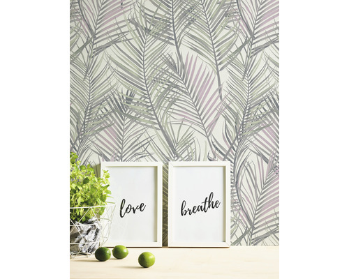 Scène avec papier peint à motif de feuilles de palmier, deux cadres photo avec les inscriptions amour et respiration, plante en pot et citrons verts