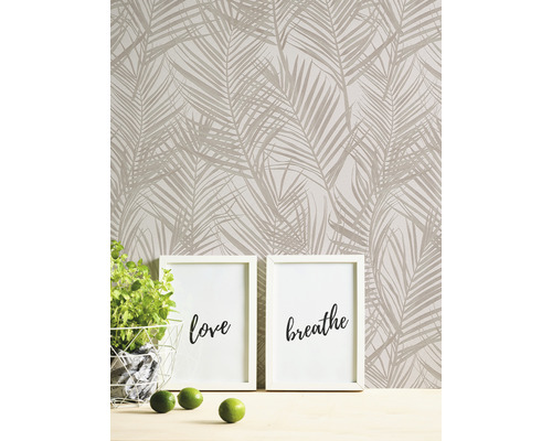 Mur avec papier peint à motifs de palmiers, deux cadres photo avec les inscriptions amour et respirer