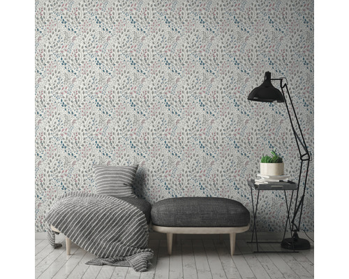 Szene mit floral gemusterter Tapete, Ottomane, Tagesdecke und Stehlampe