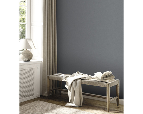 Wohnzimmer mit grauer Wand, Bank, Buch und Tagesdecke