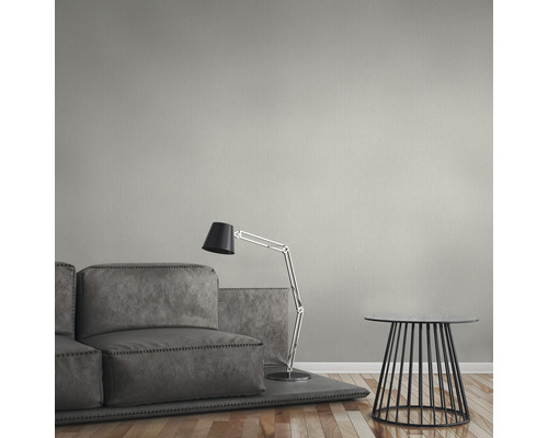 Wohnzimmer mit grauer Couch, Stehlampe und Beistelltisch vor einer einfarbigen Wand