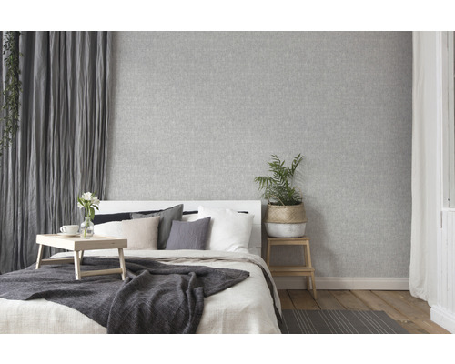 Helles Schlafzimmer mit grauer Textiltapete, Bett und Holzboden
