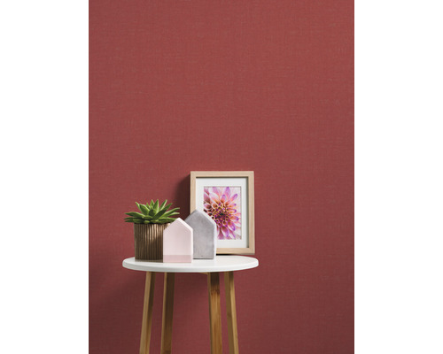 Scène décorative avec plante, maisons décoratives et cadre photo sur une table d''appoint devant un mur rouge